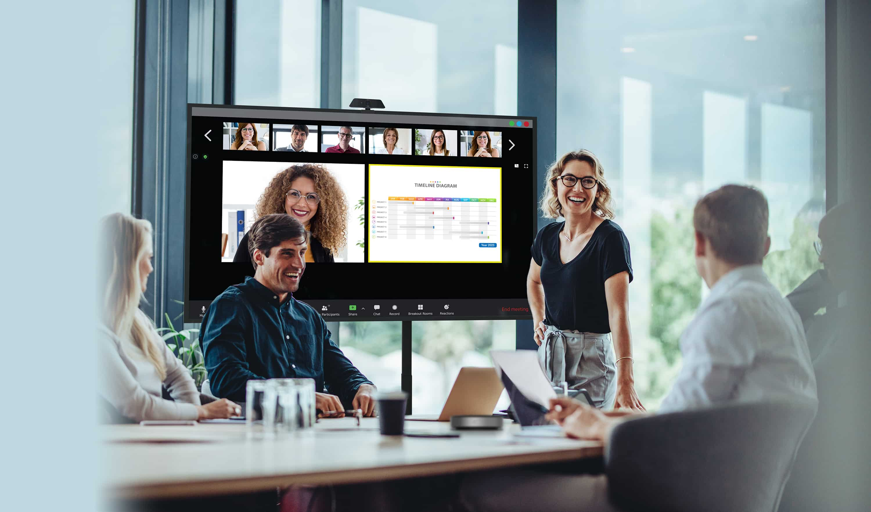 Gente llevando a cabo una reunión con parte del personal físicamente presente mirando una pantalla Optoma Serie N mientras sus compañeros de forma remota se muestran en pantalla junto al contenido que están compartiendo.